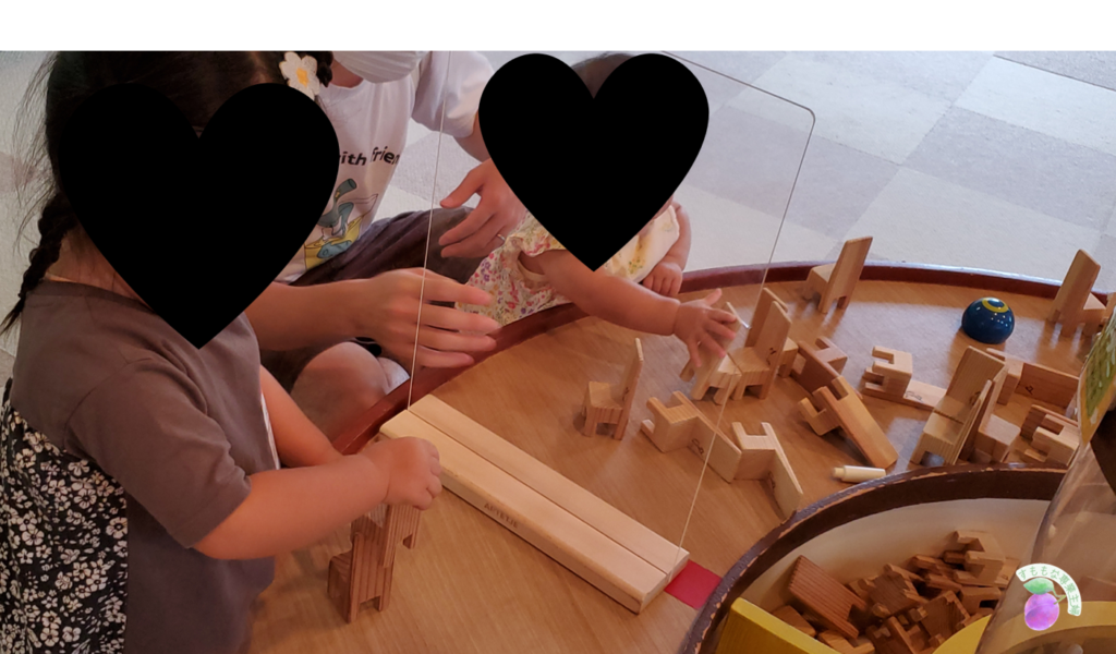 おもちゃ王国の木のおもちゃ館で遊ぶ２歳と０歳の娘たち。イスの積み木に夢中。