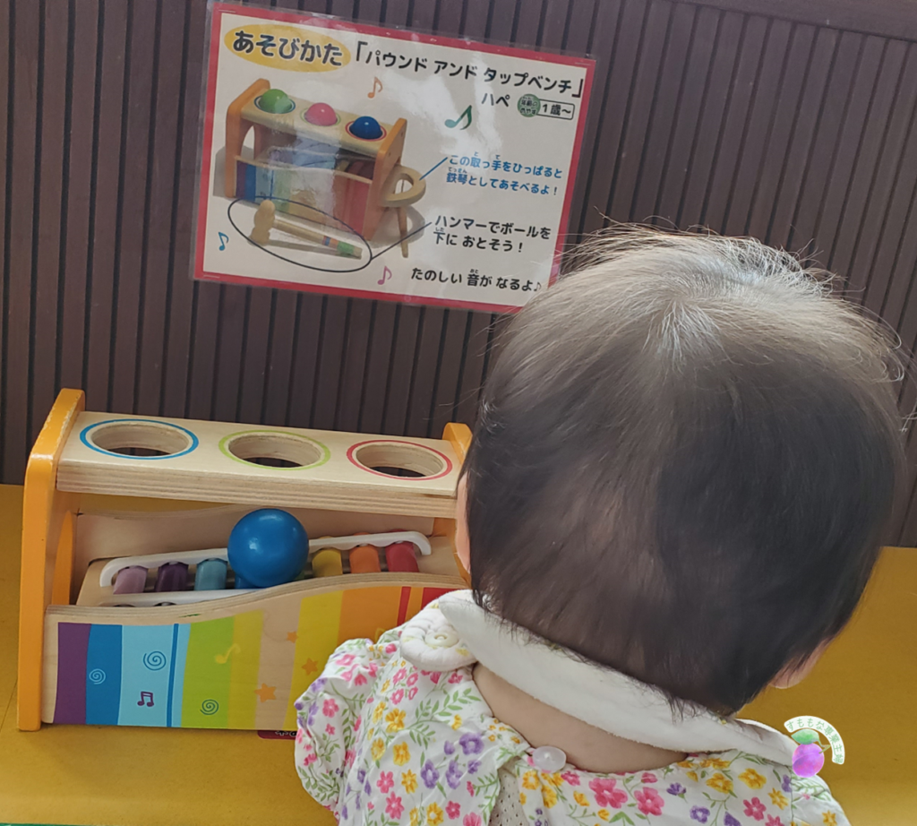 おもちゃ王国の木のおもちゃ館で遊ぶ0歳娘。パウンドアンドタップベンチに興味深々。